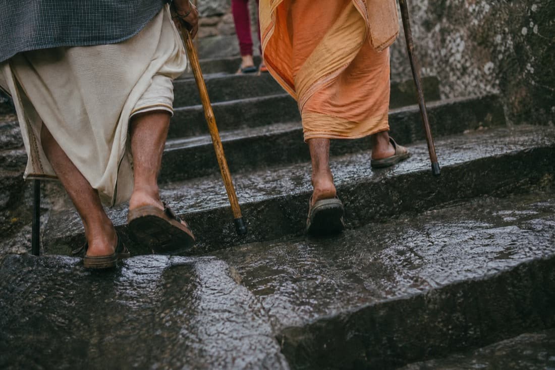 Pilgrims' feet and walking sticks on wet stone steps