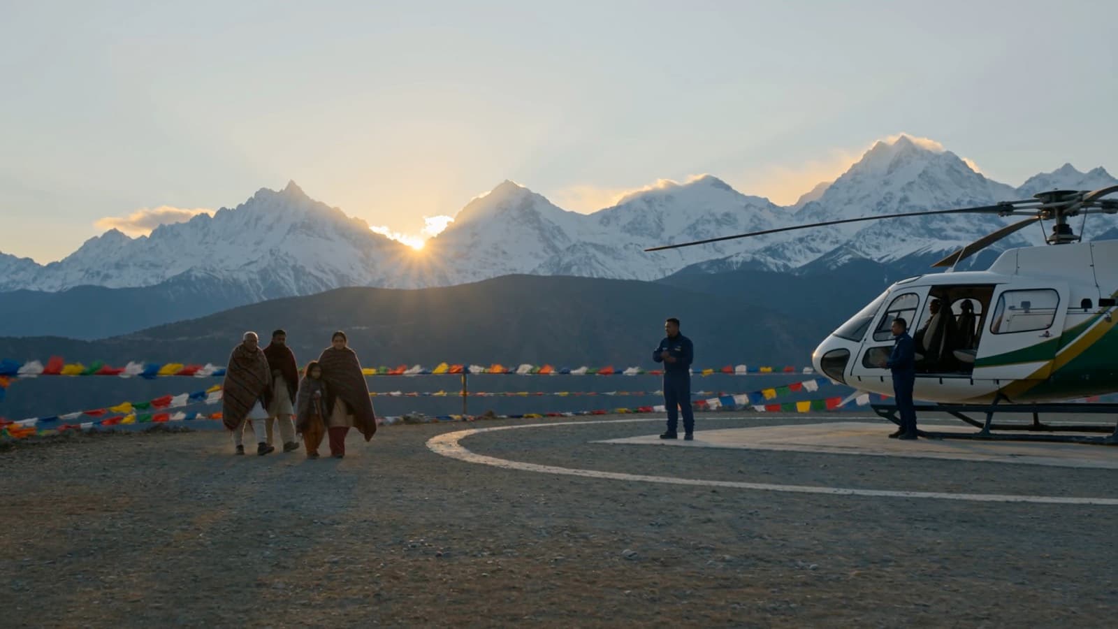 A family walking out to the helicopter at a Himalayan helipad at sunrise